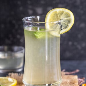 glass of lemonade topped with mint leaves and lemon