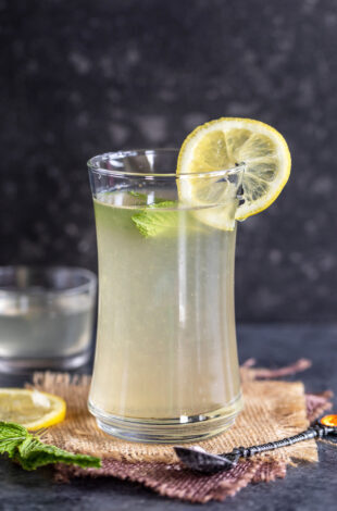 glass of lemonade topped with mint leaves and lemon