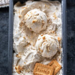 scoops of ice cream in a container with 2 parle-g biscuits placed on one side