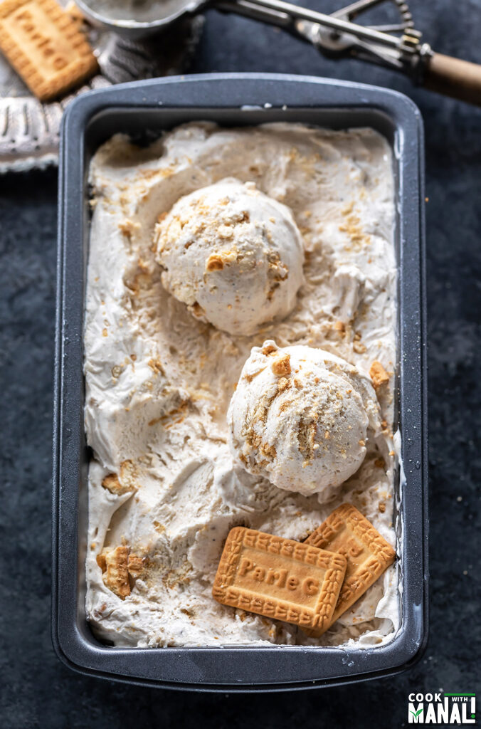 scoops of ice cream in a container with 2 parle-g biscuits placed on one side