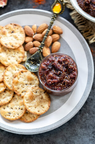 fig chutney served in a small bowl with crackers and almonds on the side
