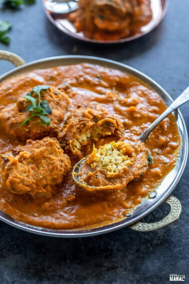 lauki kofta curry served in a copper dish with one kofta cut to show the inside