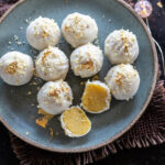badam halwa truffles placed on a blue color plate with one truffle cut in half to show the inside