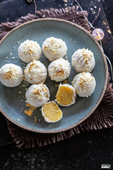 badam halwa truffles placed on a blue color plate with one truffle cut in half to show the inside