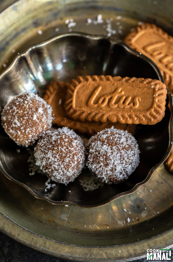 three biscoff ladoo arranged in a plate with biscoff cookies placed on one side