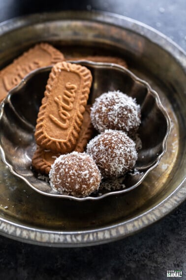 three biscoff ladoo arranged in a plate with biscoff cookies placed on one side