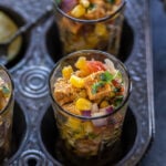 paneer and corn tossed with onion, tomatoes served in a glass and garnished with cilantro