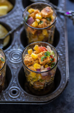 paneer and corn tossed with onion, tomatoes served in a glass and garnished with cilantro