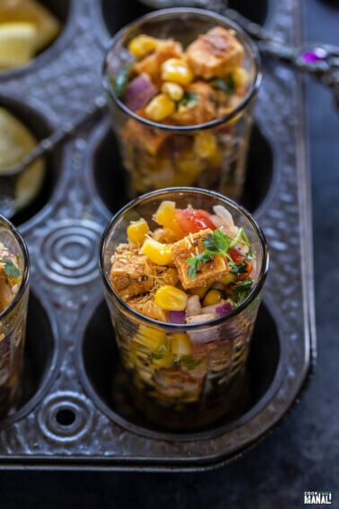 paneer and corn tossed with onion, tomatoes served in a glass and garnished with cilantro