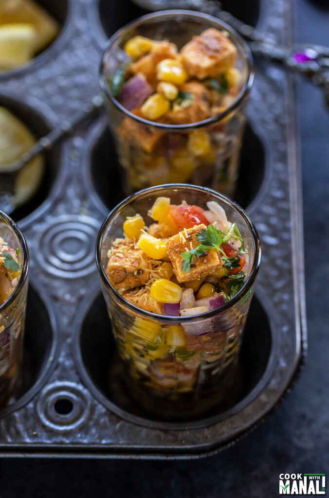 paneer and corn tossed with onion, tomatoes served in a glass and garnished with cilantro