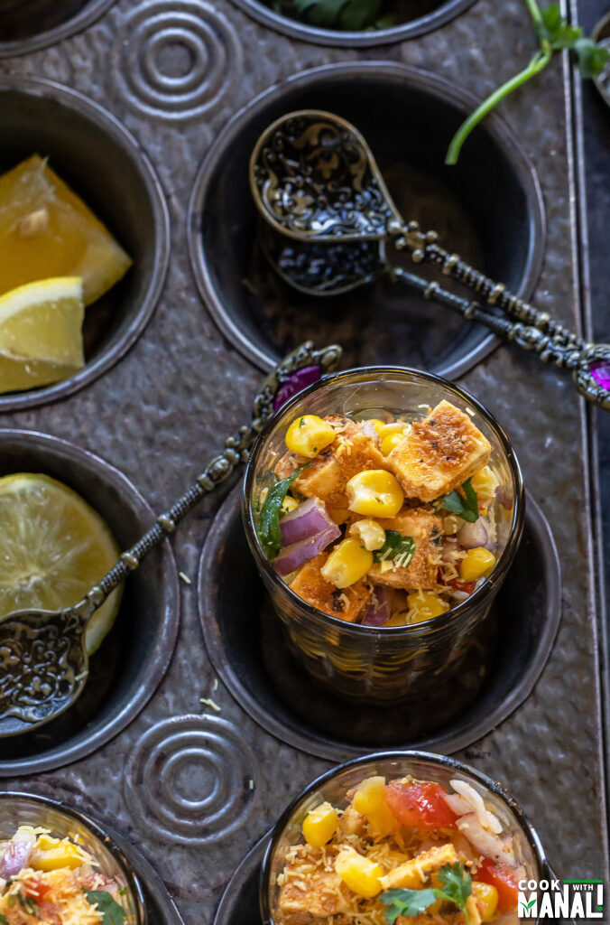 corn and paneer chaat served in small glasses with antique spoons lying on the side