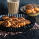 bhakarwadhi placed in a black plate with glass of chai in the background
