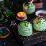 2 short glasses filled with paan mousse with a tealight placed in the background