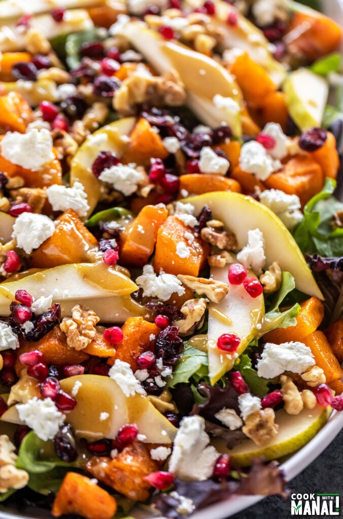 butternut squash salad with pears, goat cheese, pomegranate arranged on a plate