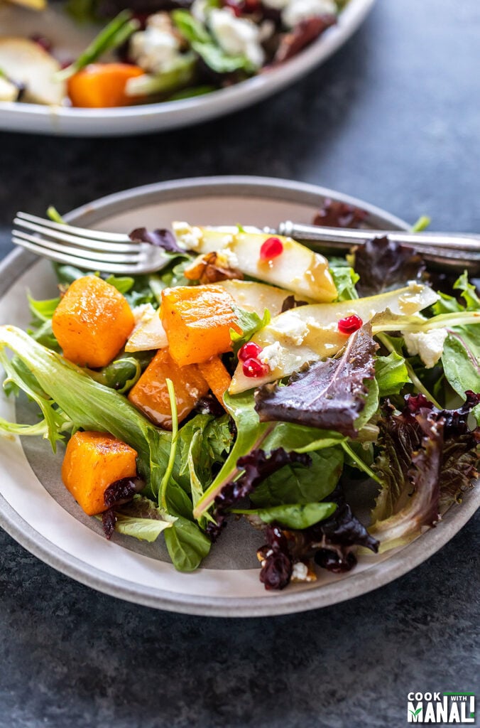 butternut squash salad with pears and pomegranate served in a round plate