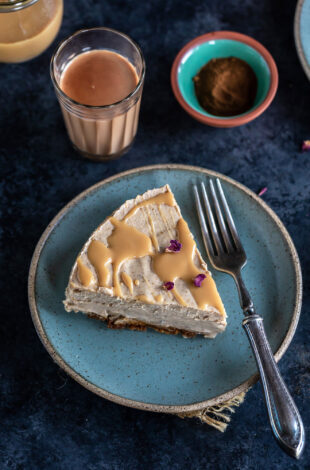 slice of masala chai cheesecake garnished with rose petals and served on a blue plate