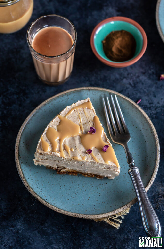slice of masala chai cheesecake garnished with rose petals and served on a blue plate