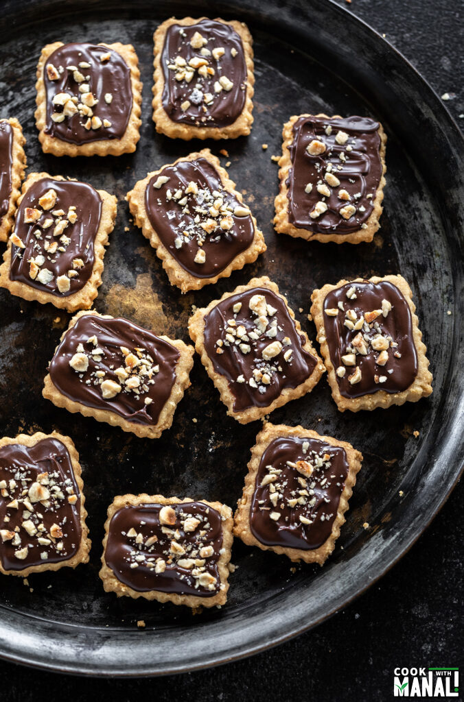 cookies topped with chocolate and hazelnuts arranged on a plate