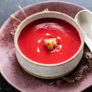 red color soup in a round ball topped with croutons