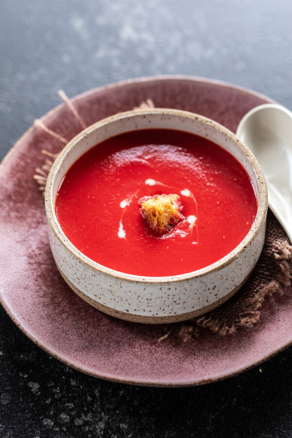 red color soup in a round ball topped with croutons