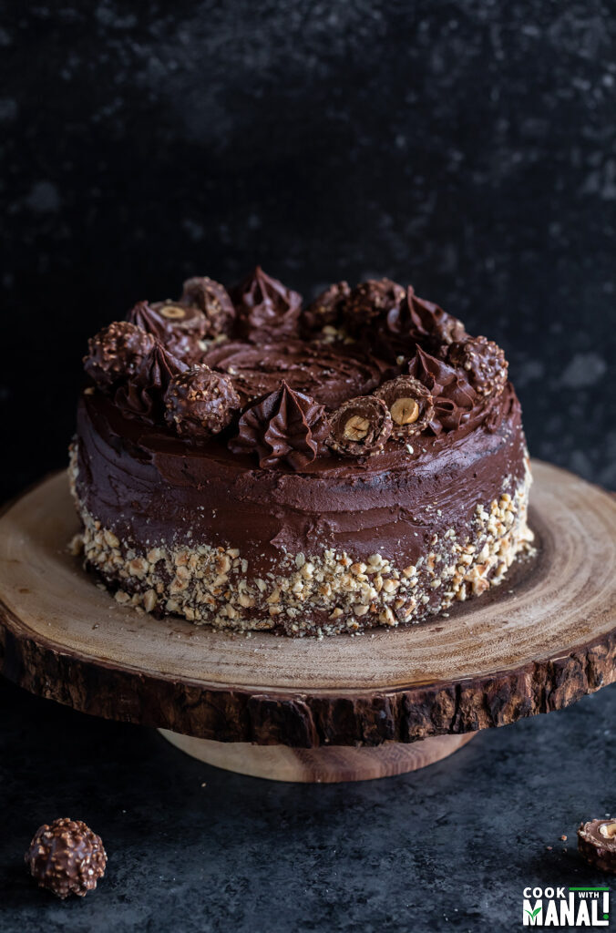 chocolate cake decorated with nuts and kept on a wooden cake stand