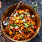 mixed vegetables cooked with spices and served in a brass bowl with spoon placed on the side