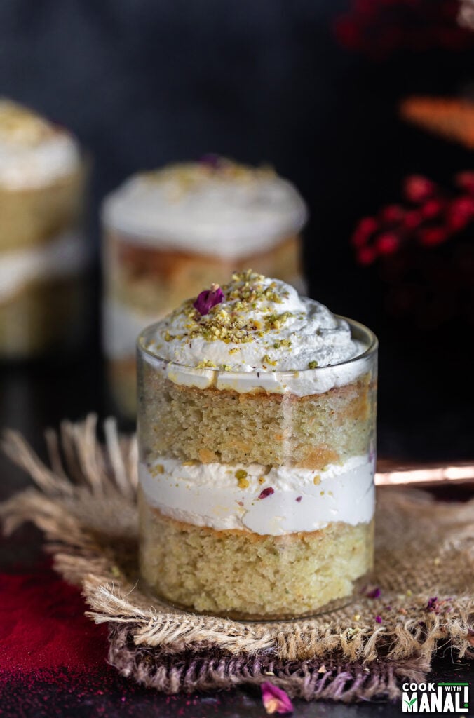 cake jars layered with cake, whipped cream with flowers placed in the background