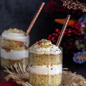 cake jars layered with cake, whipped cream with flowers placed in the background