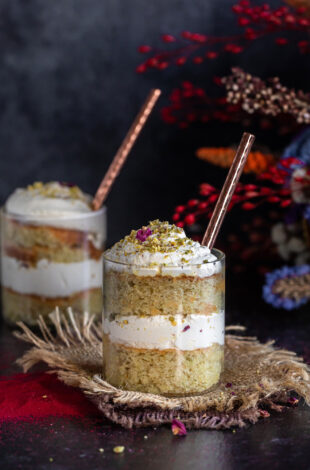 cake jars layered with cake, whipped cream with flowers placed in the background