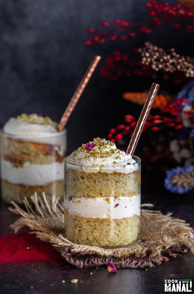 cake jars layered with cake, whipped cream with flowers placed in the background