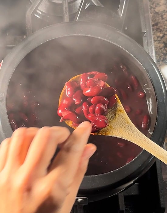 hand pressing boiled beans from a cooker