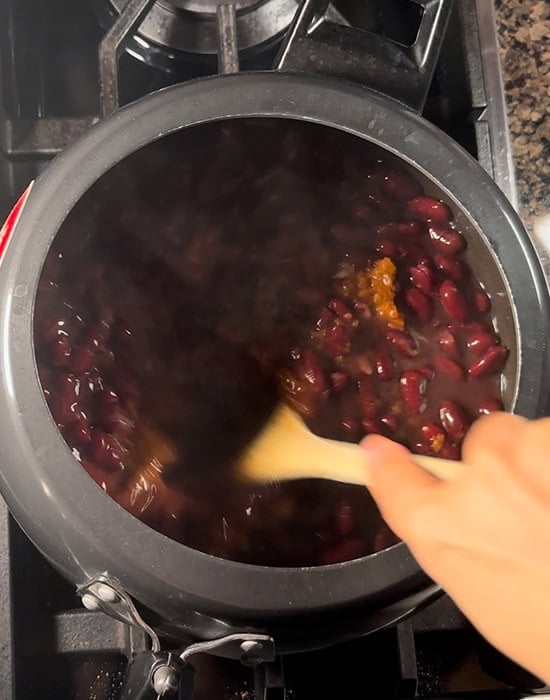 a spatula stirring rajma in pressure cooker