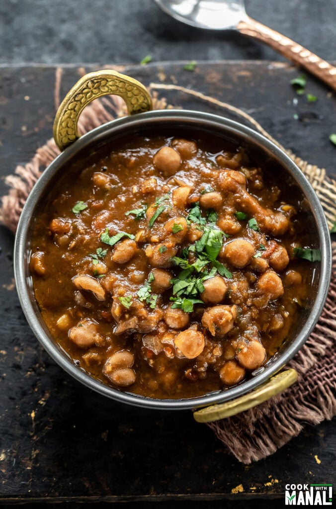 chole served in a copper kadai and garnished with cilantro