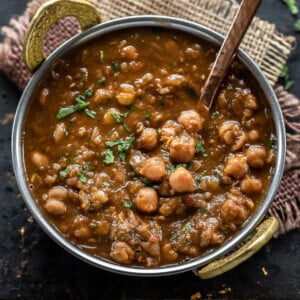 chole served in a copper kadai and garnished with cilantro