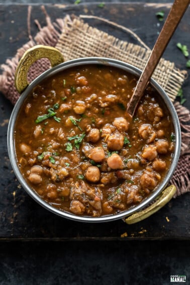 chole served in a copper kadai and garnished with cilantro