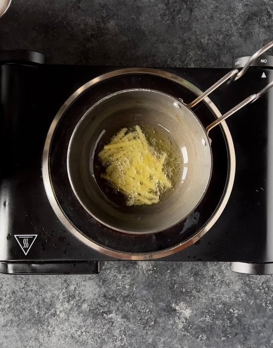 making tadka with ginger juliennes in a small pan