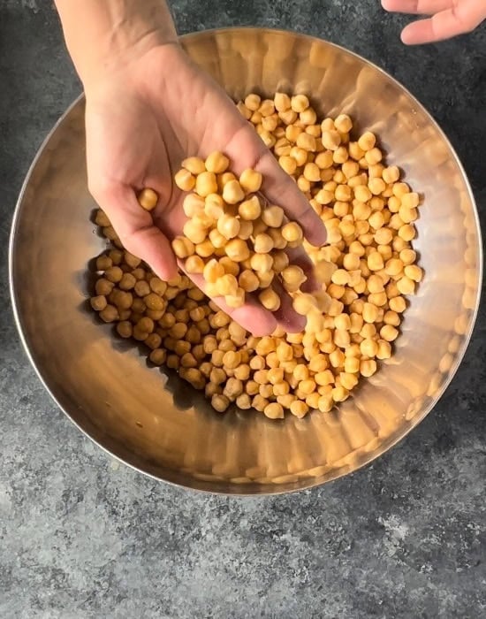 hand showing soaked chickpeas in a bowl