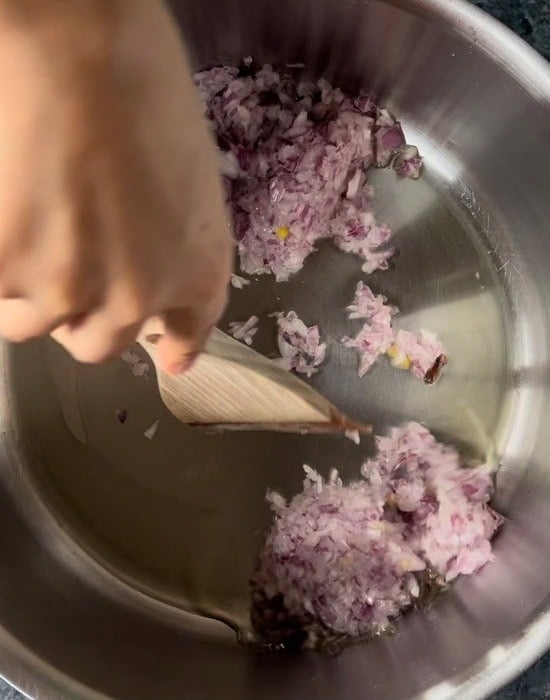wooden spatula stirring chopped onions in pot