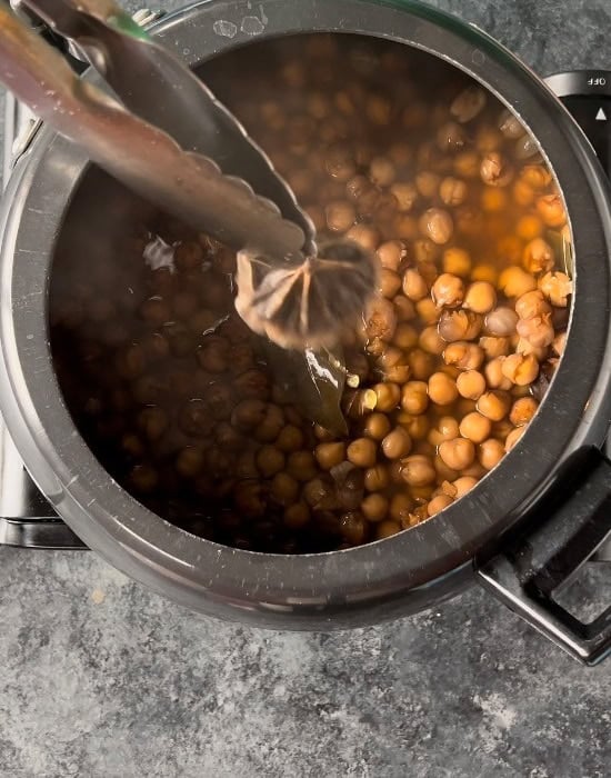 a pair of tongs picking up tea bag from pressure cooker