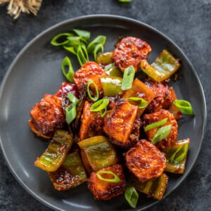 paneer cubes tossed in sauce garnished with green onions