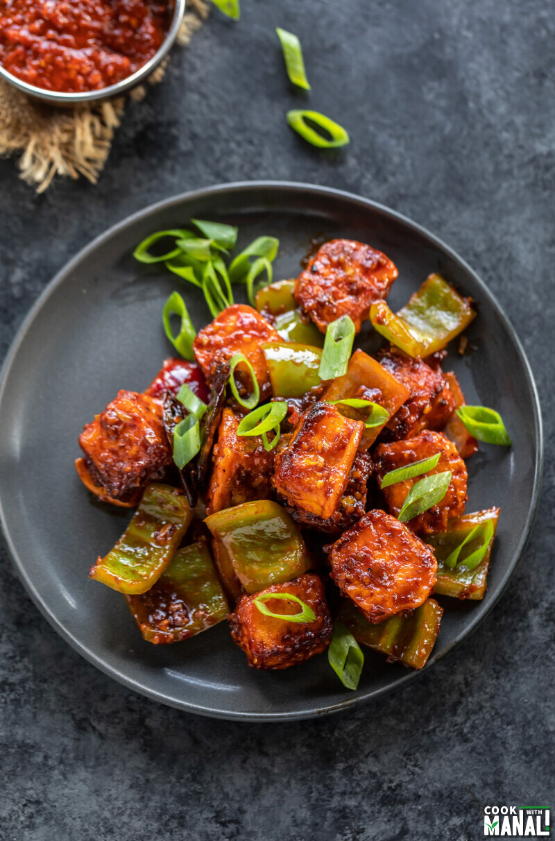 paneer cubes tossed in sauce garnished with green onions