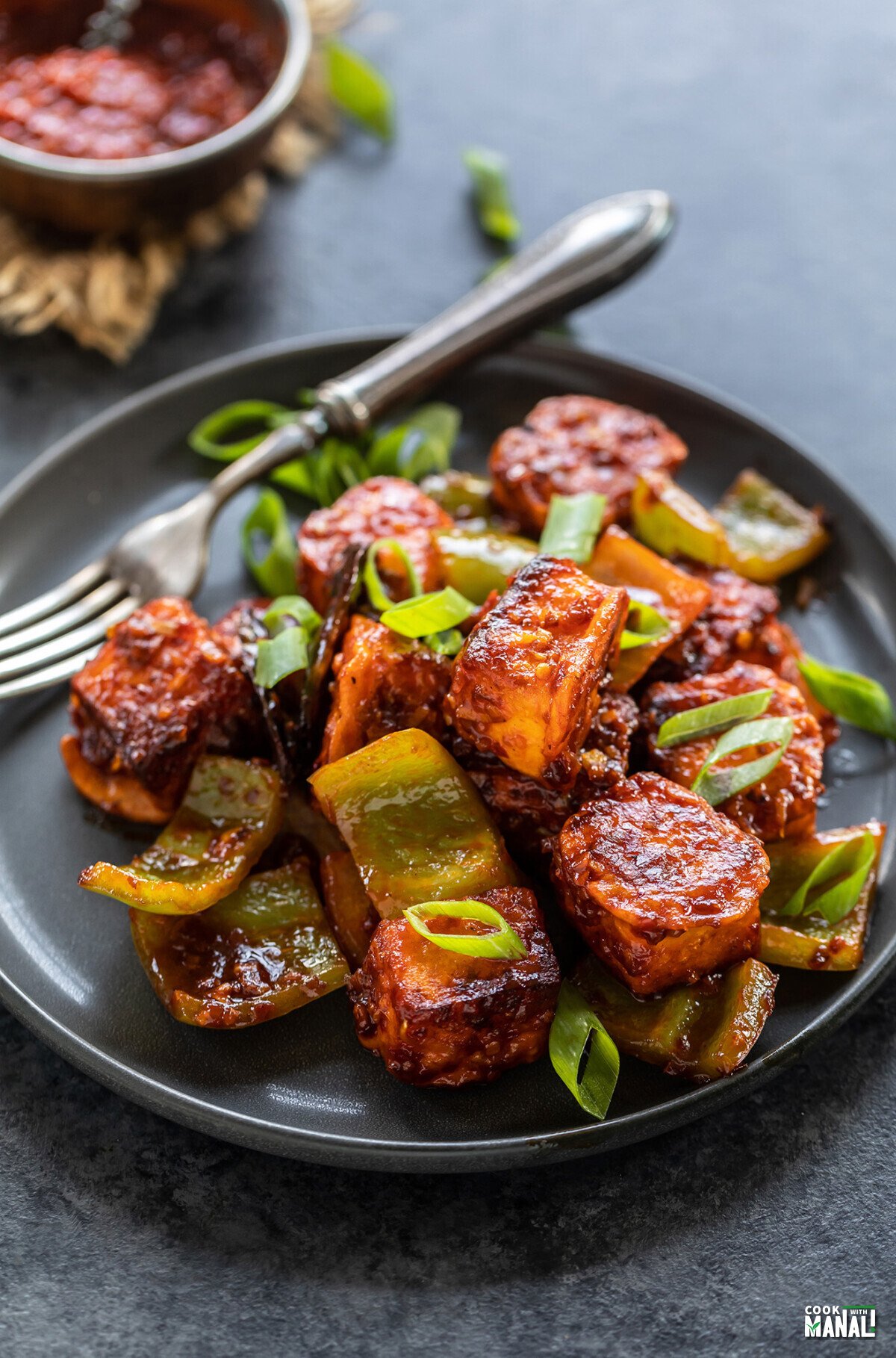 paneer cubes tossed in sauce garnished with green onions