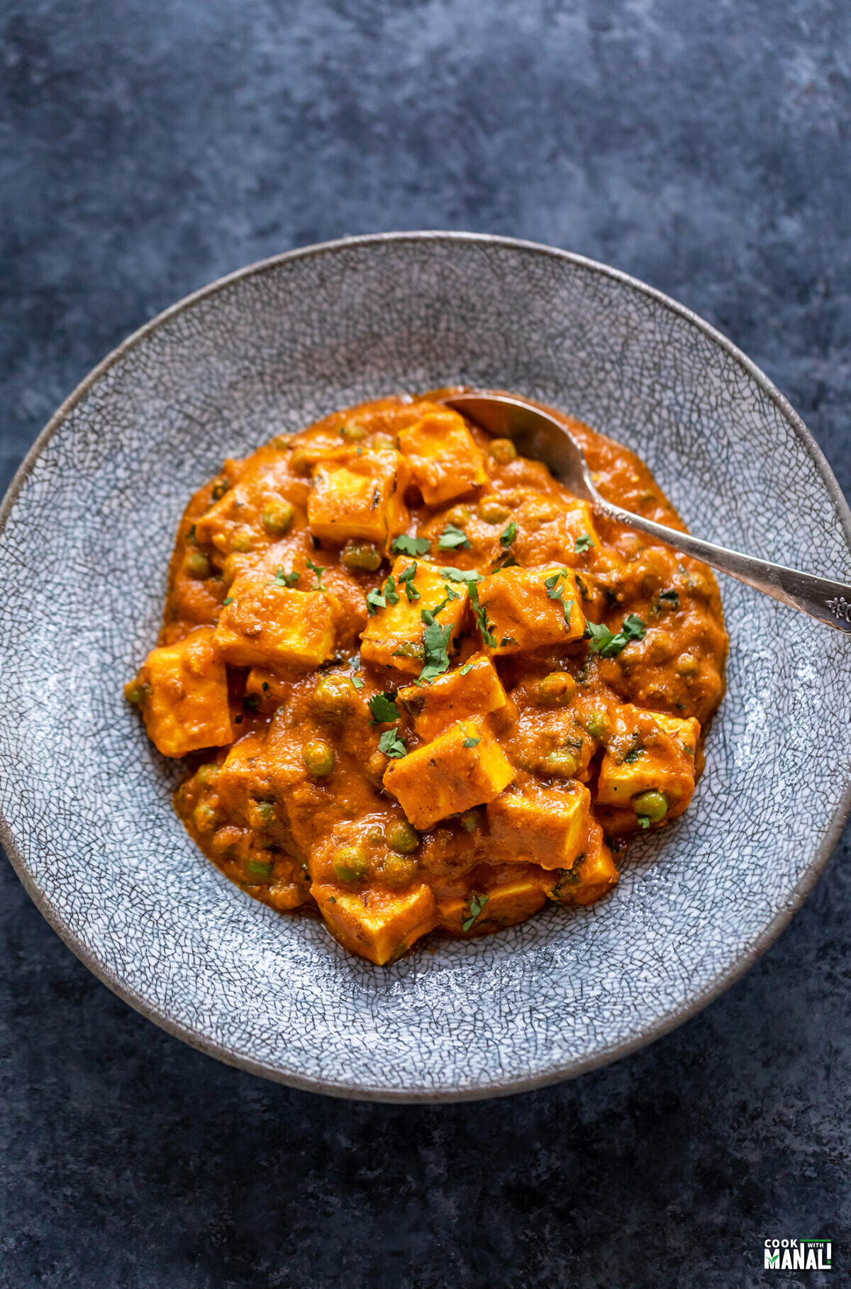 matar paneer served in a bowl with spoon on the side