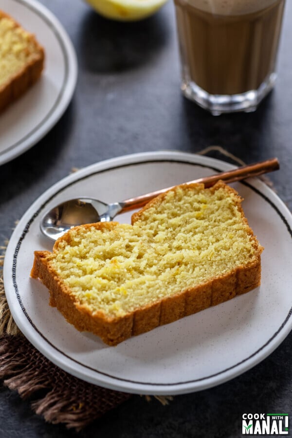 slice of lemon cake placed on a white plate with copper spoon on the side