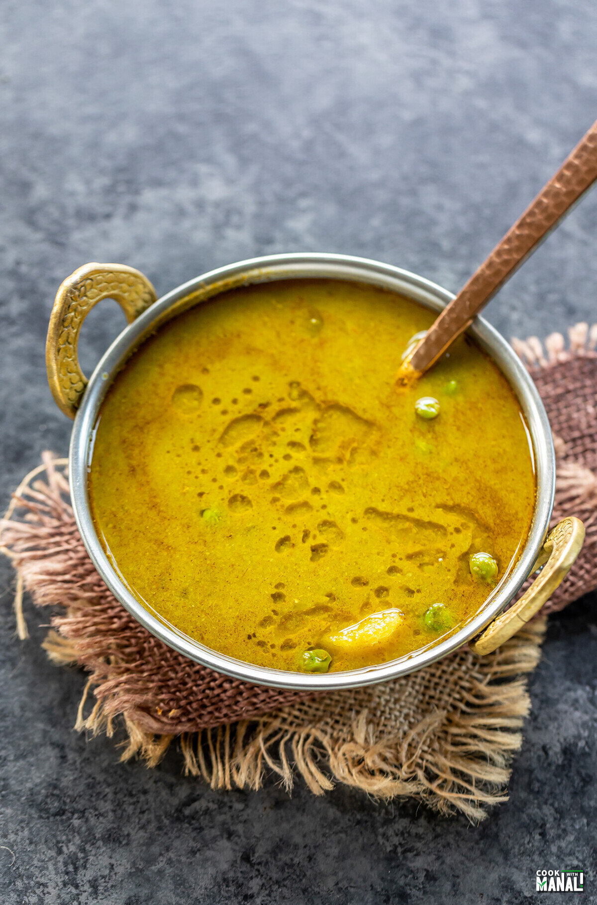 yellow-green curry served in a copper kadai