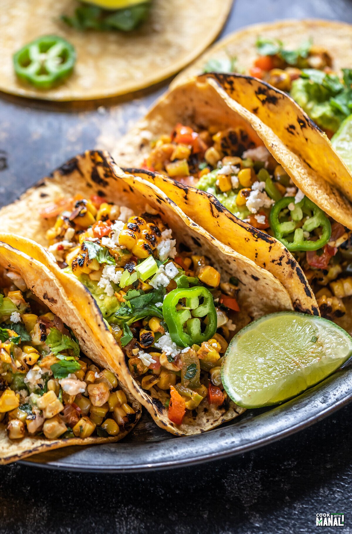 grilled corn tacos arranged on a plate with a lime wedge placed on the side