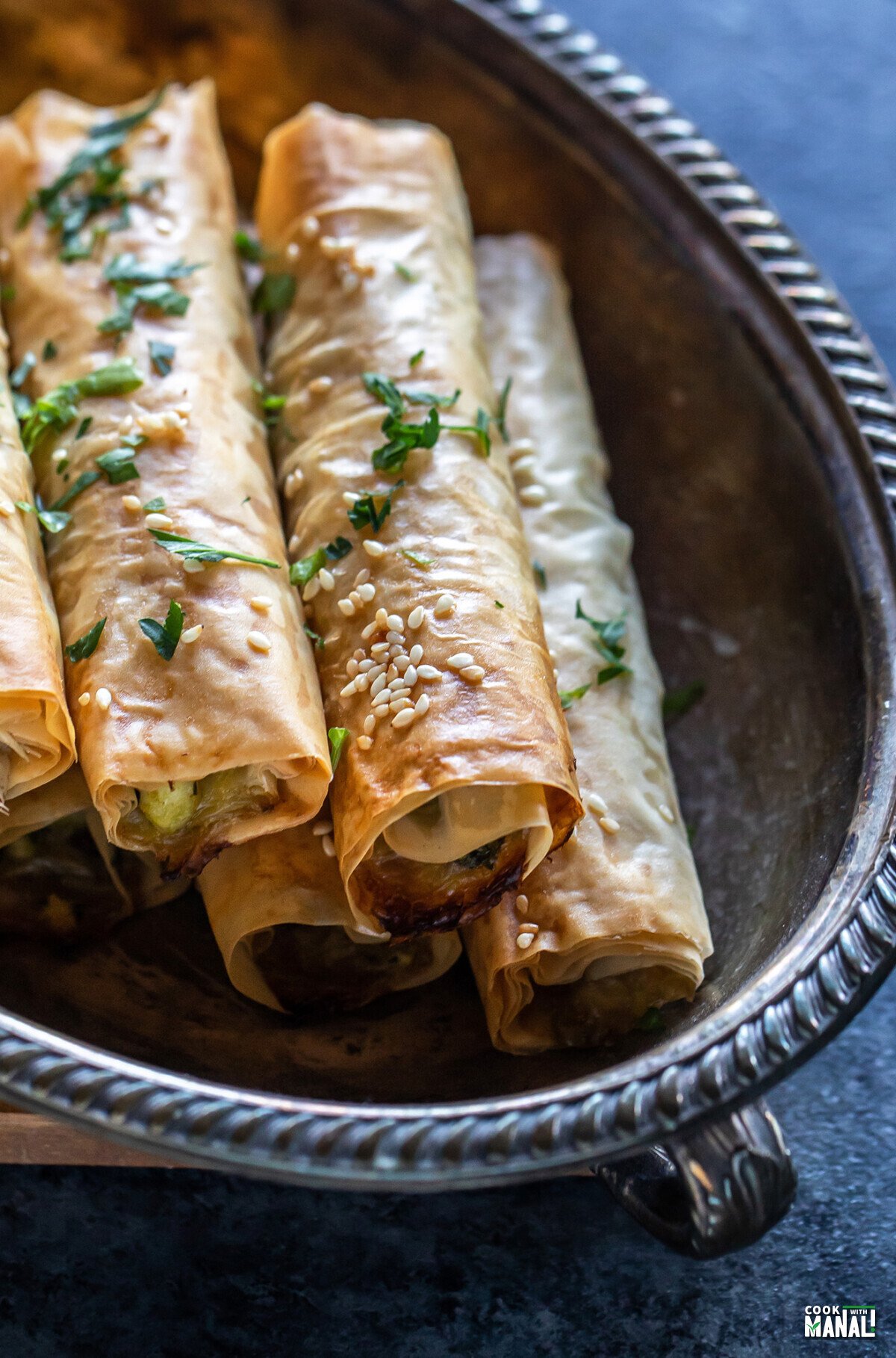 phyllo dough rolls arranged on an oval serving plate and garnished with parsley