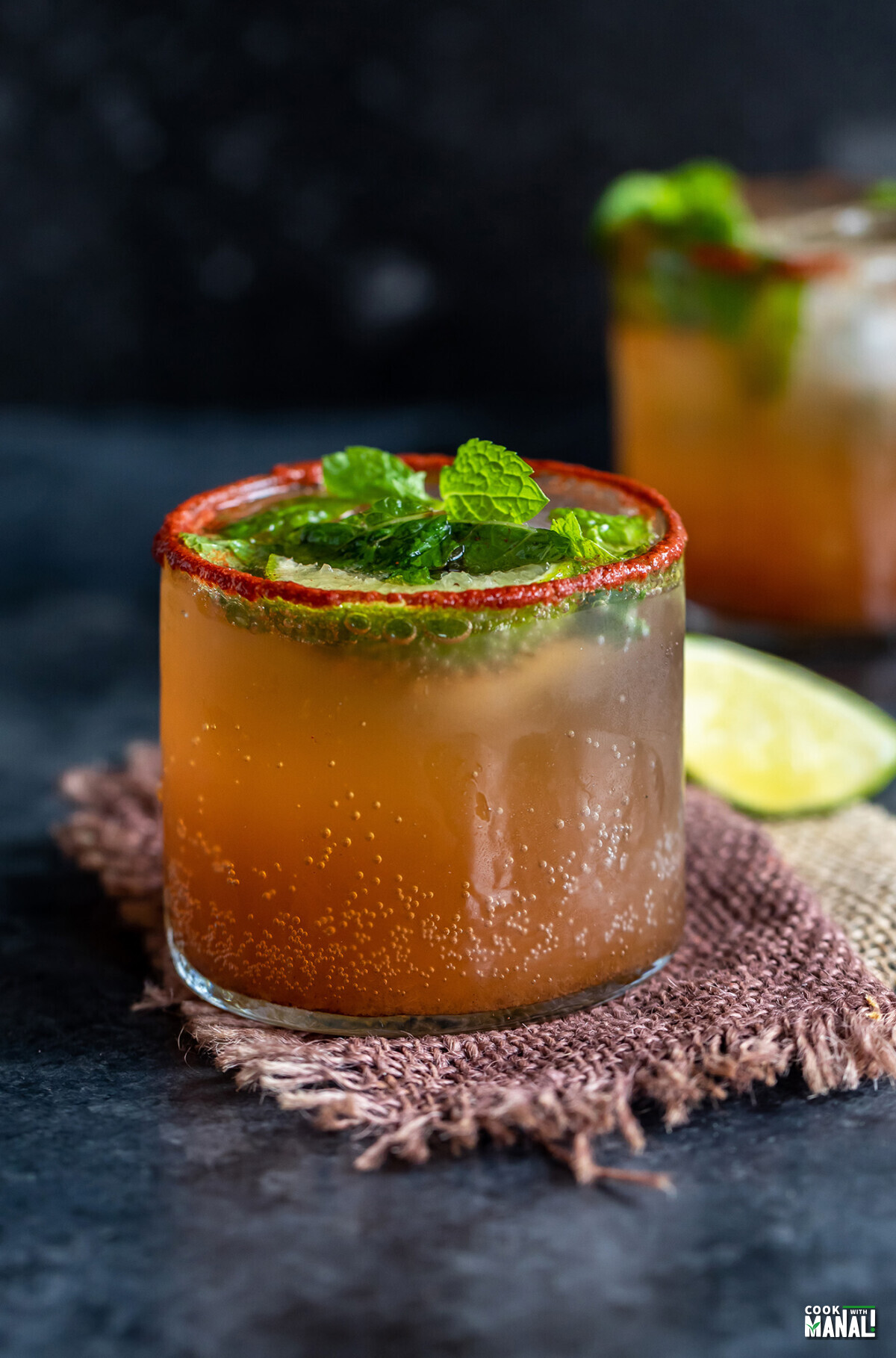 tamarind drink served in a glass topped with mint leaves and lemon wedges