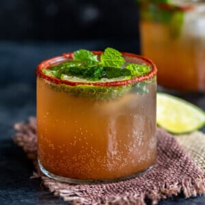 tamarind drink served in a glass topped with mint leaves and lemon wedges