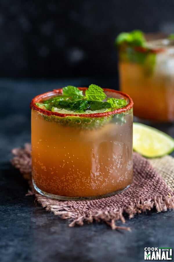 tamarind drink served in a glass topped with mint leaves and lemon wedges